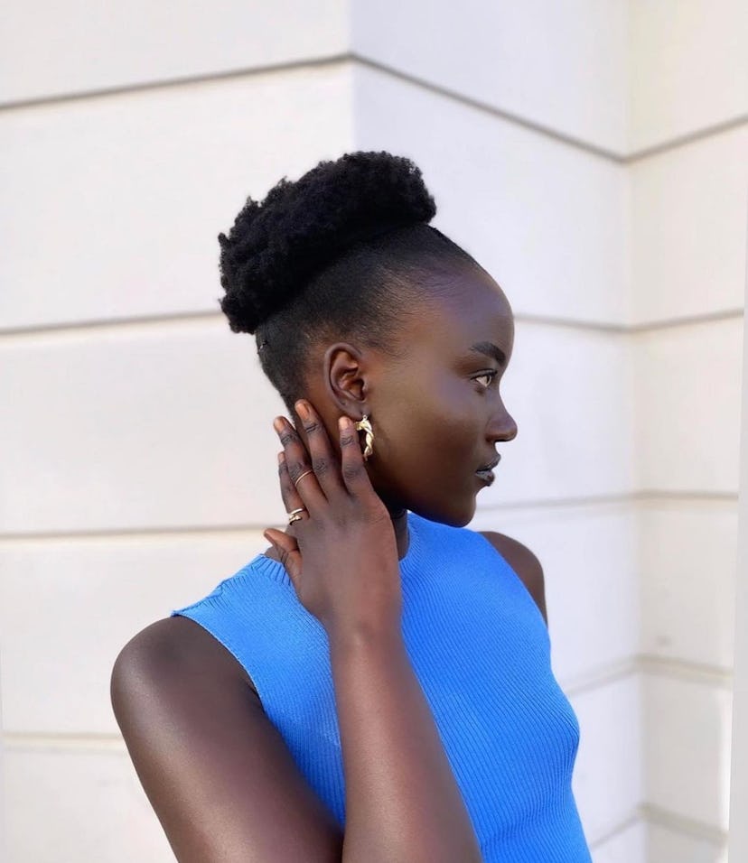 Model posing with hand up by neck in profile