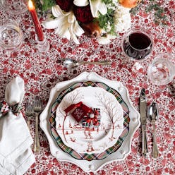 A decorative holiday plate on a patterned holiday tablecloth with other holiday details