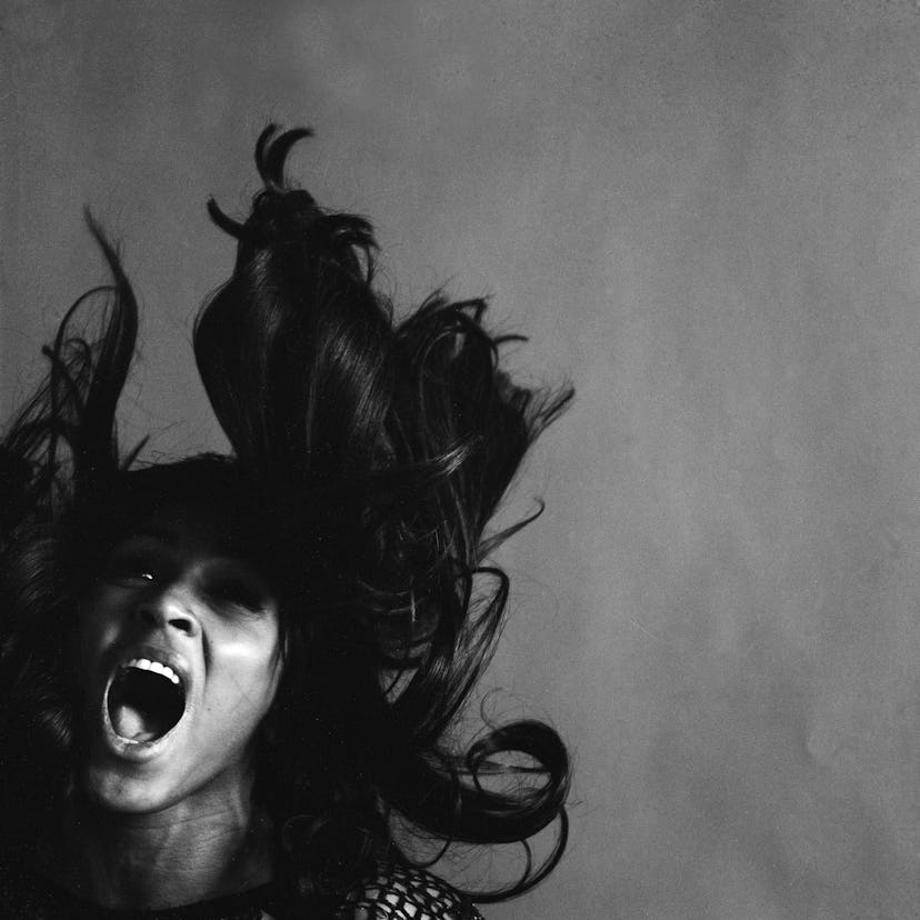 American rock singer Tina Turner, wearing a dark crocheted mini-dress, singing while her long dark h...