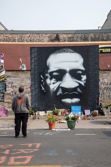 Minneapolis, Minnesota, African American man standing at the mural of George Floyd killed by police....