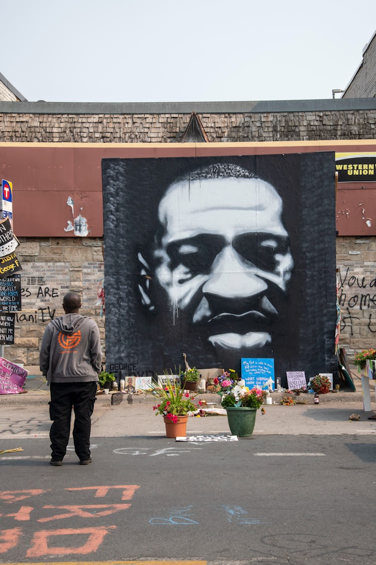 Minneapolis, Minnesota, African American man standing at the mural of George Floyd killed by police....