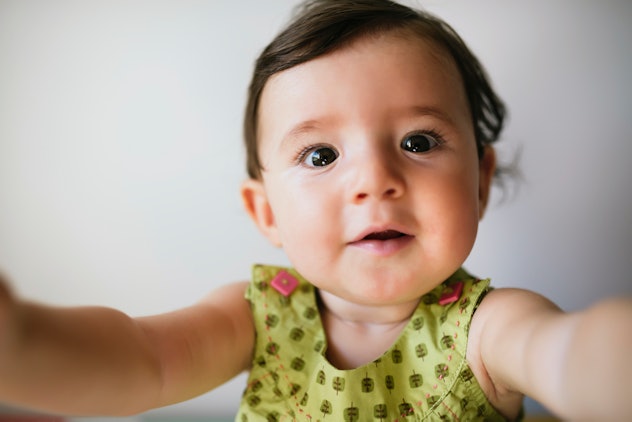 Baby holds camera and smiles in an article about new year baby names.