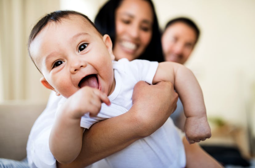 Mom holds happy, smiling baby close to camera in an article about new year baby names.