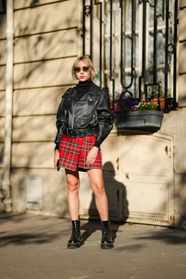 Emy Venturini a red plaid mini skirt, a leather jacket, and combat boots in Paris, France.