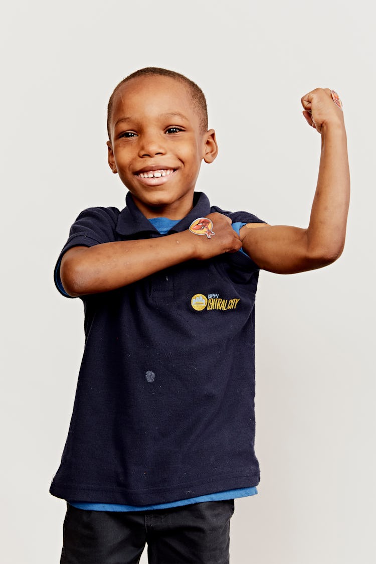 A young boy flexes his muscle, showing off his vaccine band-aid