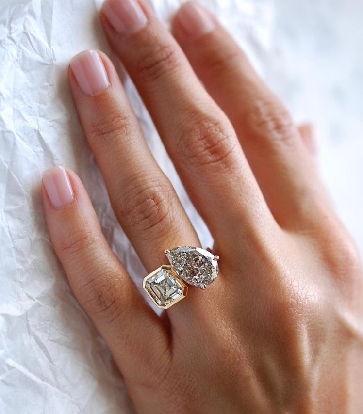 A toi et moi engagement ring featuring a white asscher cut diamond and imperfect salt and pepper dia...
