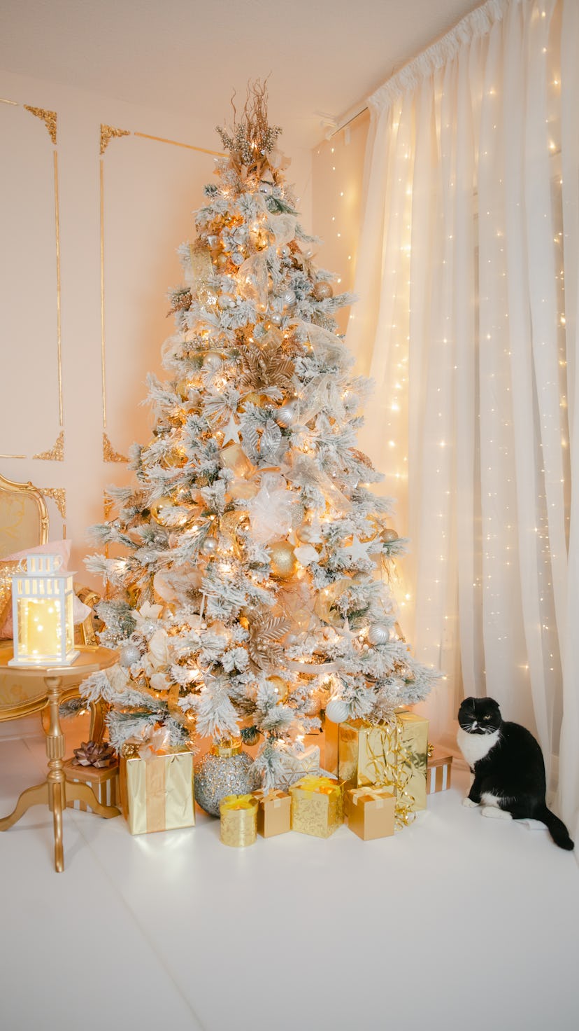modern snow-covered christmas tree covered in gold and metallic ornaments