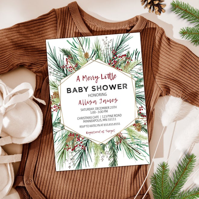 Christmas baby shower invitation laying on top of a baby onesie