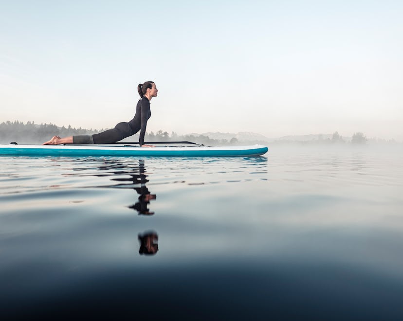woman stretching and balancing on a paddle board