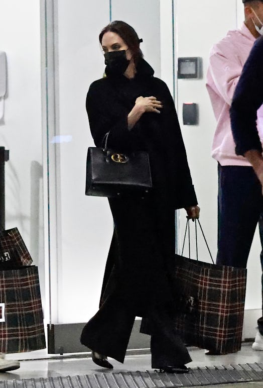 Angelina Jolie wearing a black top and trousers and carrying Dior's St. Honore Bag.