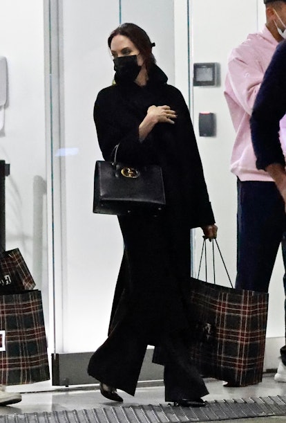 Angelina Jolie wearing a black top and trousers and carrying Dior's St. Honore Bag.