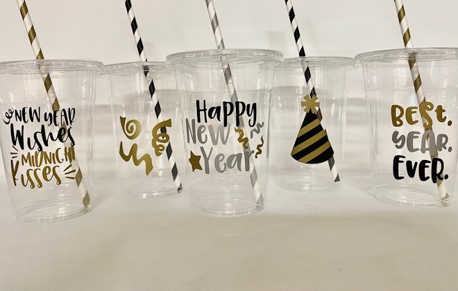 Several clear drinking cups with New Year details, with black and gold straws