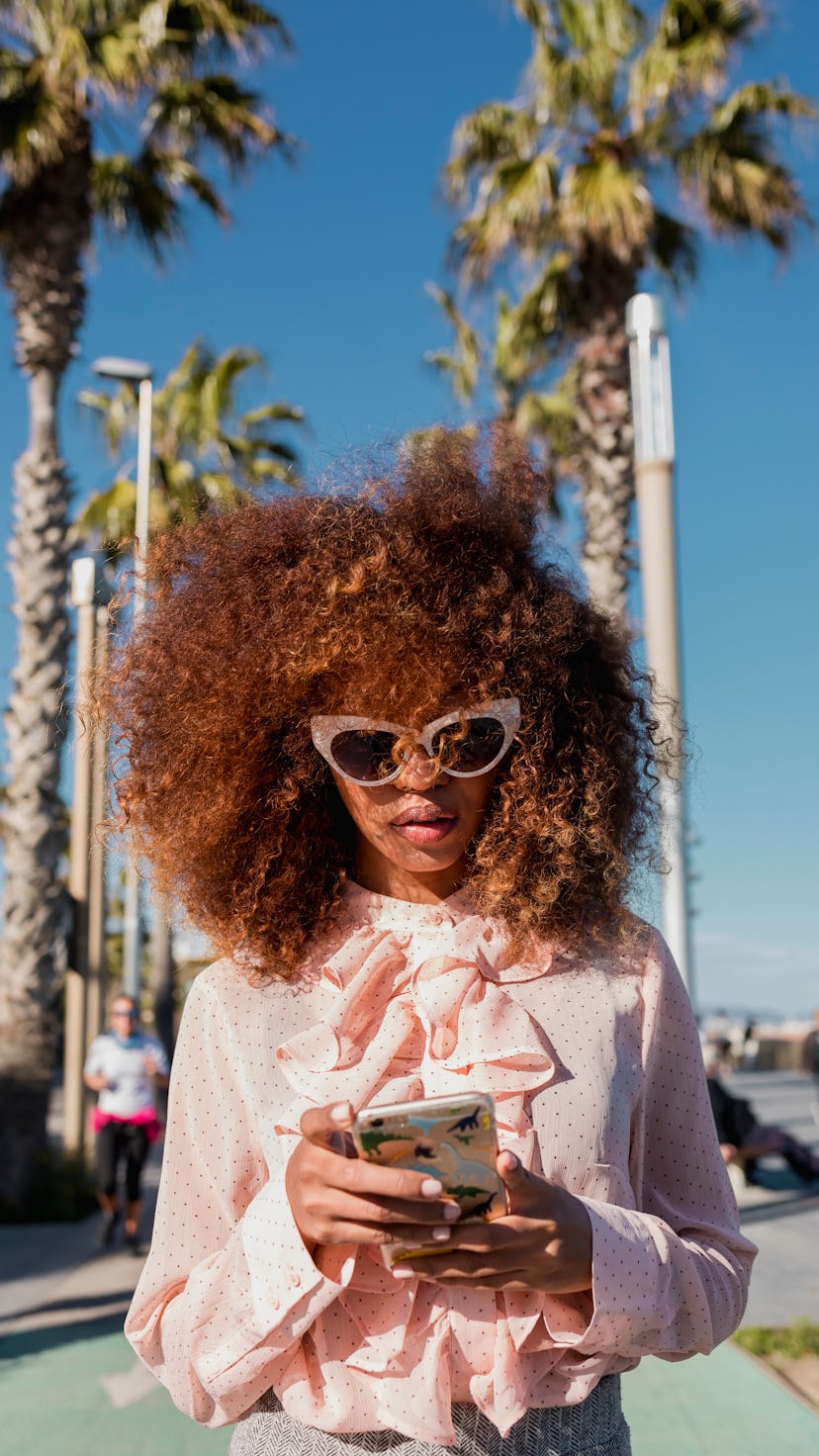 Young woman on her phone, wondering the best place for her to travel in 2022, per her zodiac sign.