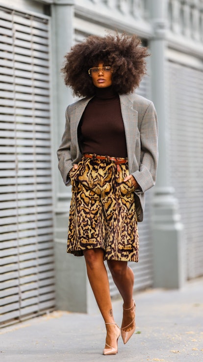 Alicia Aylies wears a brown sweater, taupe blazer, and animal print skirt.