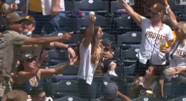 Lexy Whitmore catches a ball at a Padres game while holding her son, Maverick