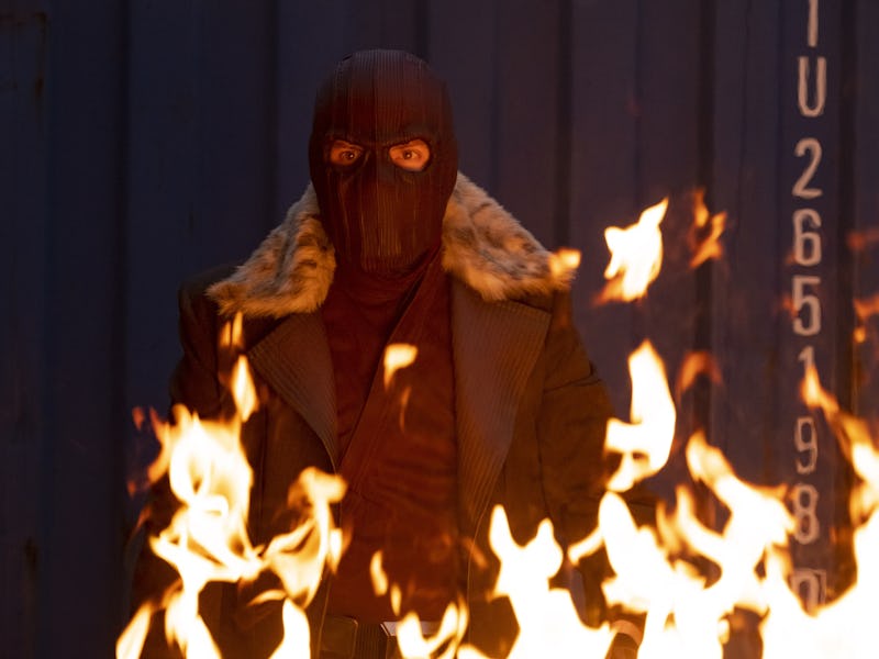 Marvel character wearing a black mask while fire is burning in front of him