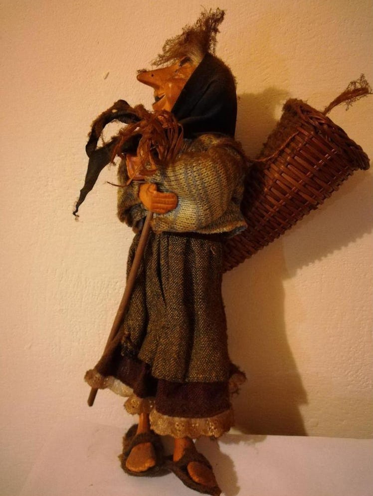 The italian christmas witch la befana with a broom in hand and a wicker basket on her back