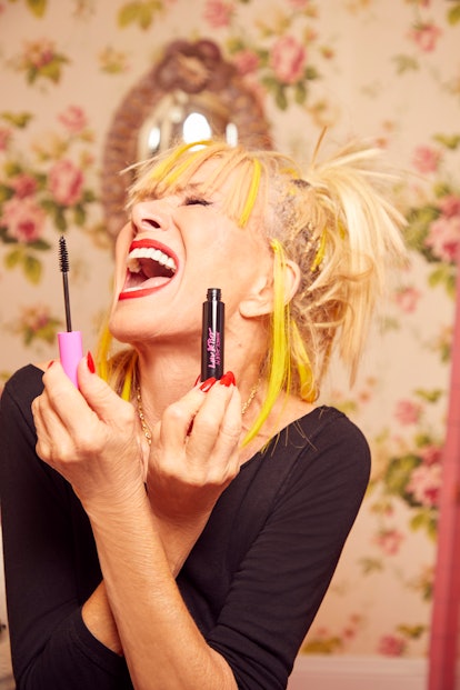 American fashion designer Betsey Johnson holding mascara in her hand and smiling widely