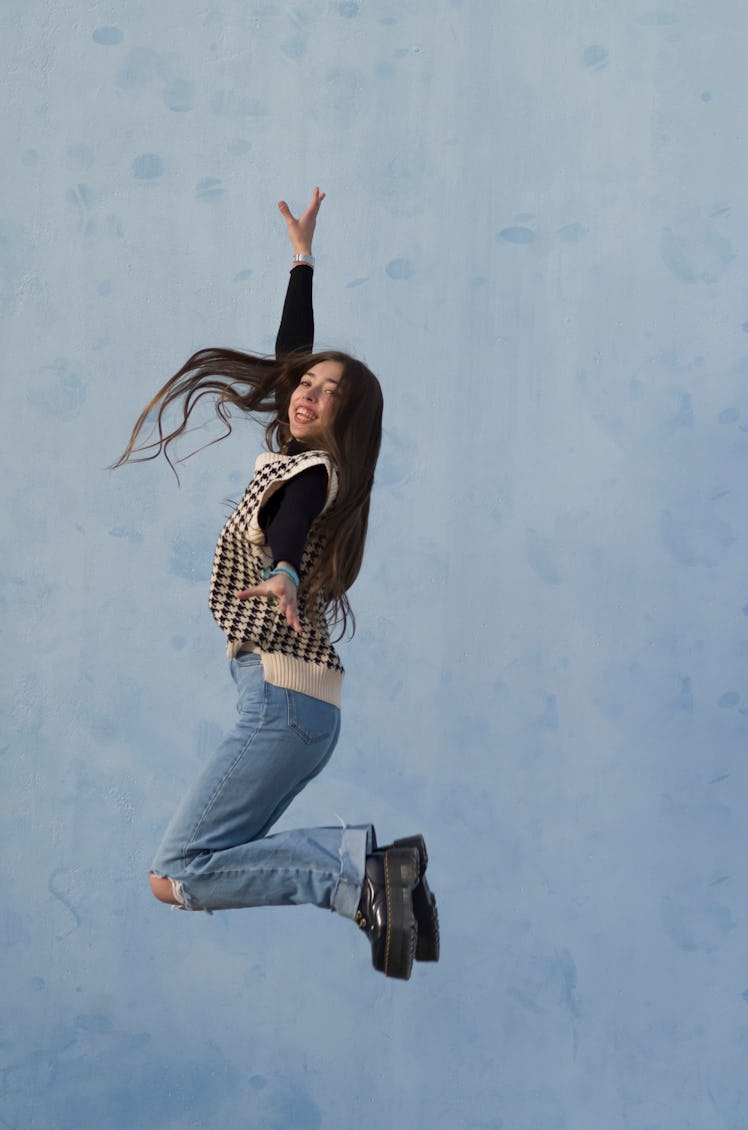 Young woman jumping in the air after learning she's one of the luckiest zodiac signs of 2022.