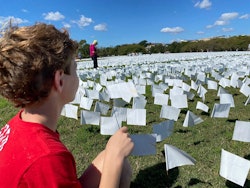 A boy plants a white flag at the memorial installation for Covid-19 victims at the National Mall in ...
