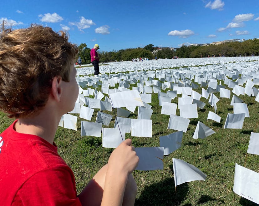 A boy plants a white flag at the memorial installation for Covid-19 victims at the National Mall in ...