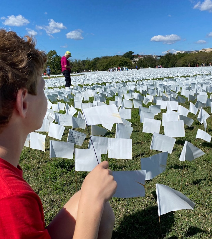 A boy plants a white flag at the memorial installation for Covid-19 victims at the National Mall in ...