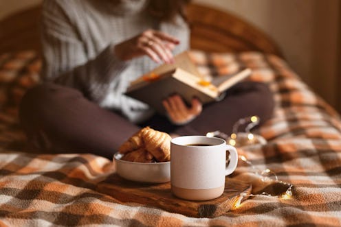 cozy autumn evening: girl, coffee, book and croissants