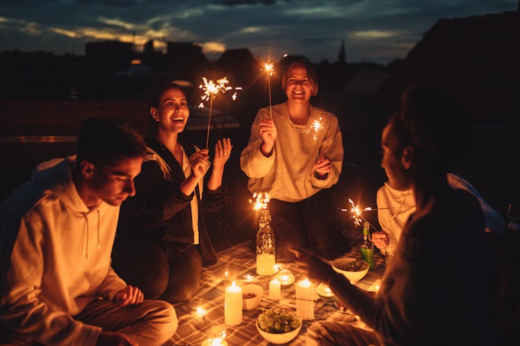 Young friends lighting sparklers after reading their 2022 yearly horoscope.