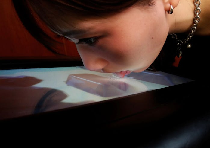 A demonstrator licks the screen of Taste the TV (TTTV), a prototype lickable TV screen that can imit...