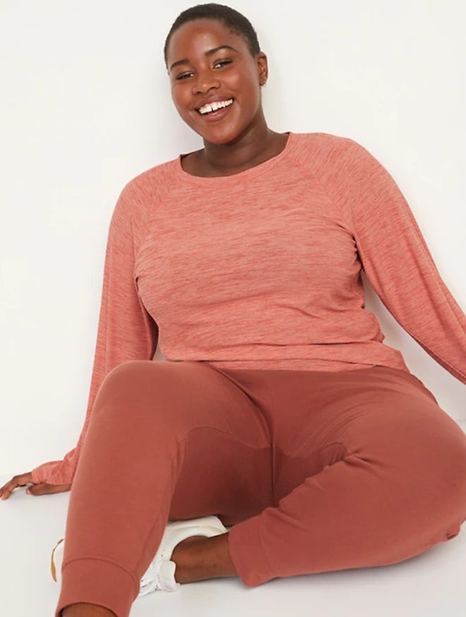 Woman sitting, smiling, modeling pink long sleeve top