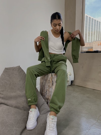 Woman sitting, modeling dark green lounge pants