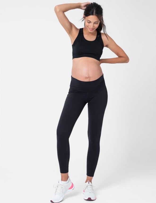Pregnant woman standing, modeling black workout pants