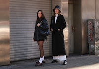 Gina Walser and Karla Jenders wearing a black blazer and loafers and a black coat.