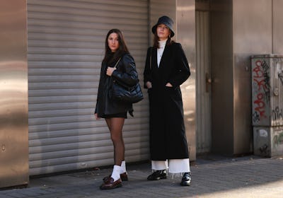 Gina Walser and Karla Jenders wearing a black blazer and loafers and a black coat.