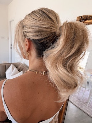 Blonde hair styled into a fluffy and wavy ponytail.