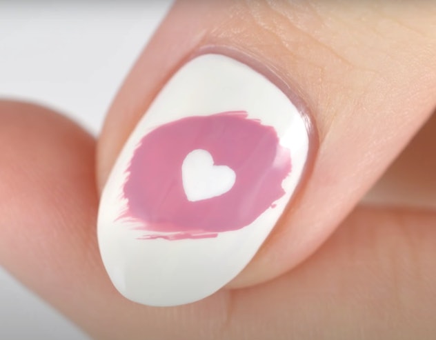Close up of nail with white polish, a swish of pink polish, and a white heart