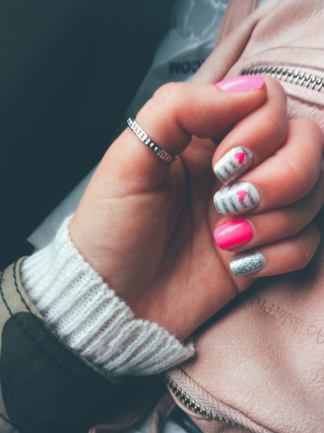 Manicure; each finger different with variations of white, pink, and silver glitter polishes