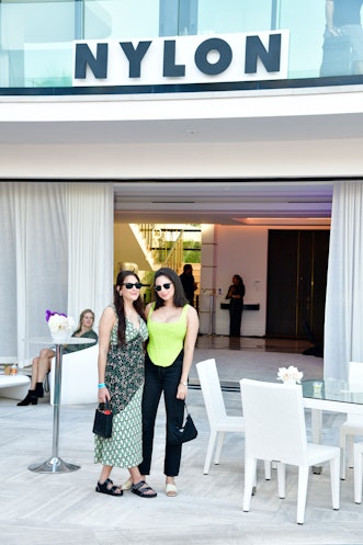 Two women with glasses posing in front of the NYLON sign at Art Basel Miami
