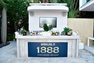The white stand for Brugal 1888 with plants around, inside NYLON house at Art Basel Miami