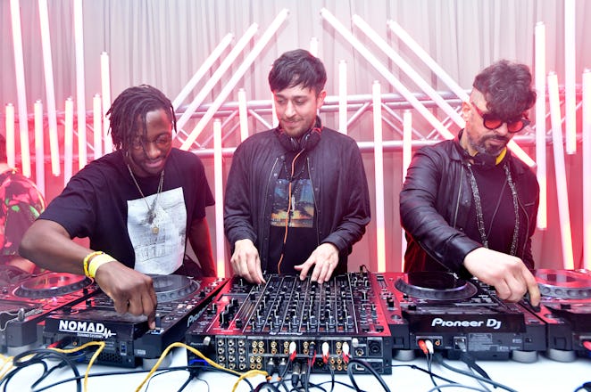 Three male DJs standing behind a mixing board at Art Basel Miami