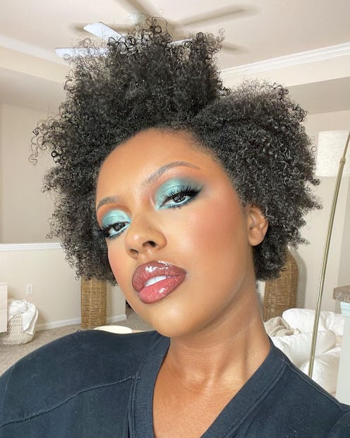 A curly-haired model wearing one of the best cream eyeshadows for effortless application in green