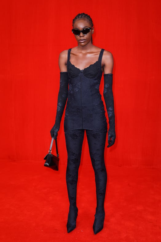 Model on a red background wearing a full black Balenciaga outfit with floral textures and oversized ...