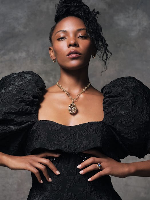 A dancer posing in jewelry and a black dress with puffy sleeves