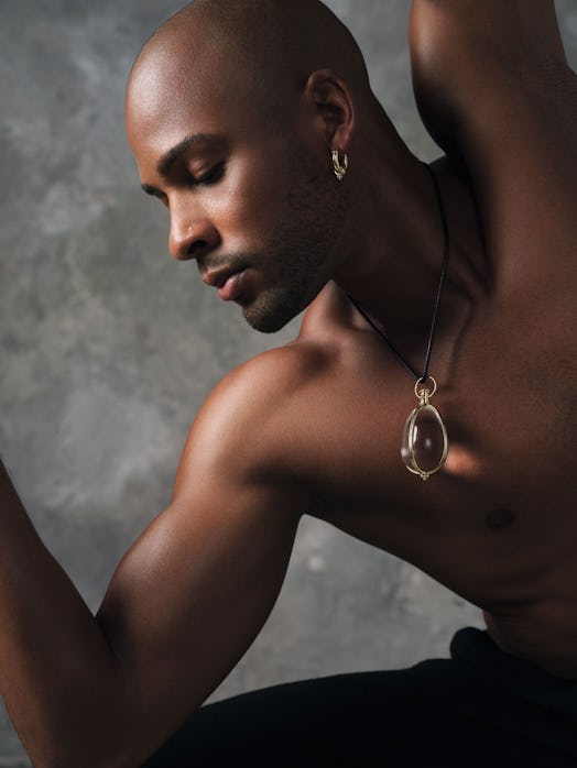 A dancer posing shirtless in jewelry and black pants