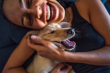 Young woman cuddles with happy puppy