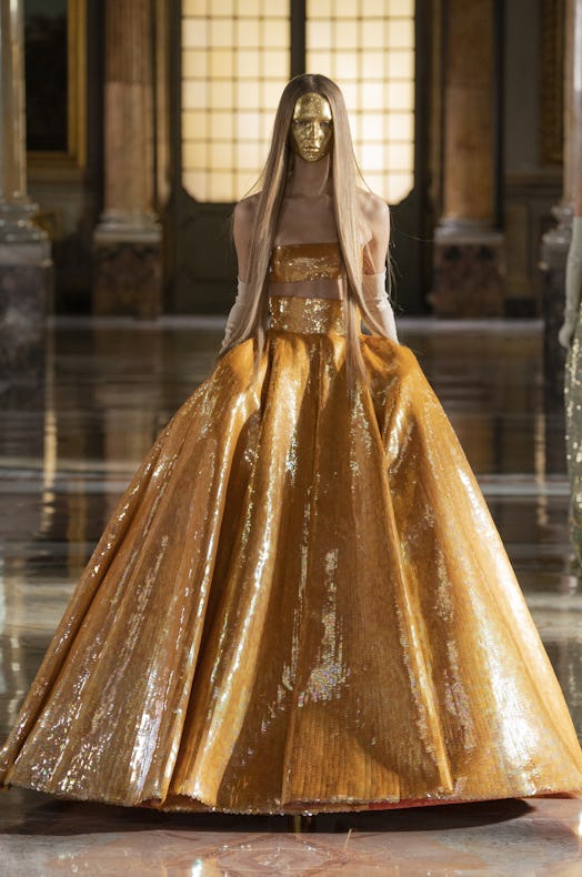 The model wears a long shimmery gown and a golden mask from Valentino Haute Couture Spring/Summer 20...