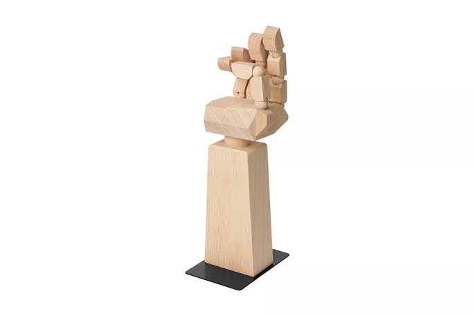 A wooden hand with half a forearm, the fingers pointing upward, can be seen on a white surface. 