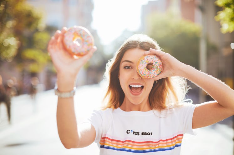 Woman holding two sprinkled donuts