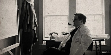 A black-and-white photo of Edward Page smoking a pipe in a lab coat