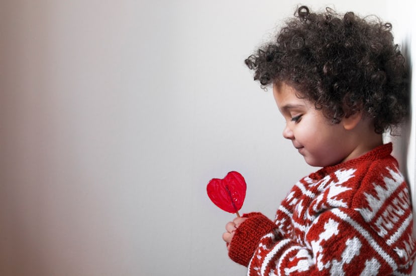 child holding and looking at a heart-shaped lollipop in an article about valentine's day poems for k...